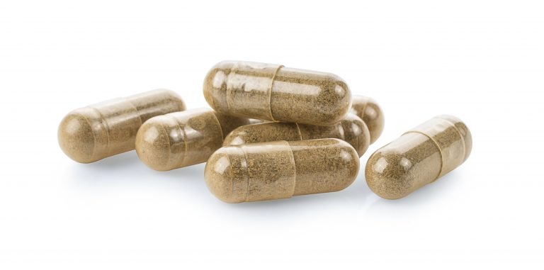 Herbal supplement capsules on a white surface.